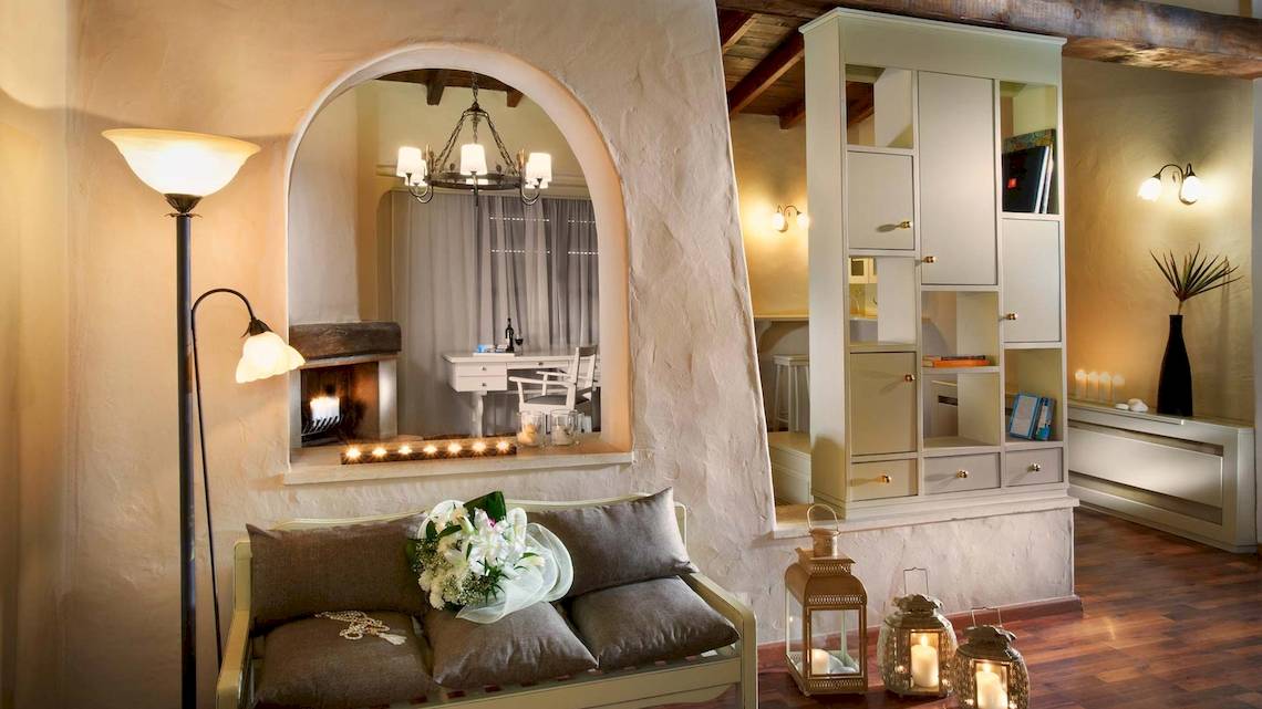 Innenansicht eines Zimmers im Acrotel Athena Pallas mit Couch, Kamin und Dekor.