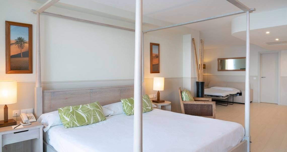Doppelbett Zimmer im Vincci Tenerife Golf Hotel mit vier weißen Säulen, weißen Wänden und grünen Kissen.