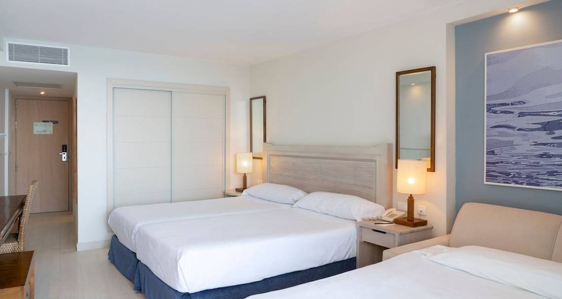 Doppelzimmer im Vincci Tenerife Golf Hotel mit zwei Betten, Nachttischen, Lampen und einem Sofa.