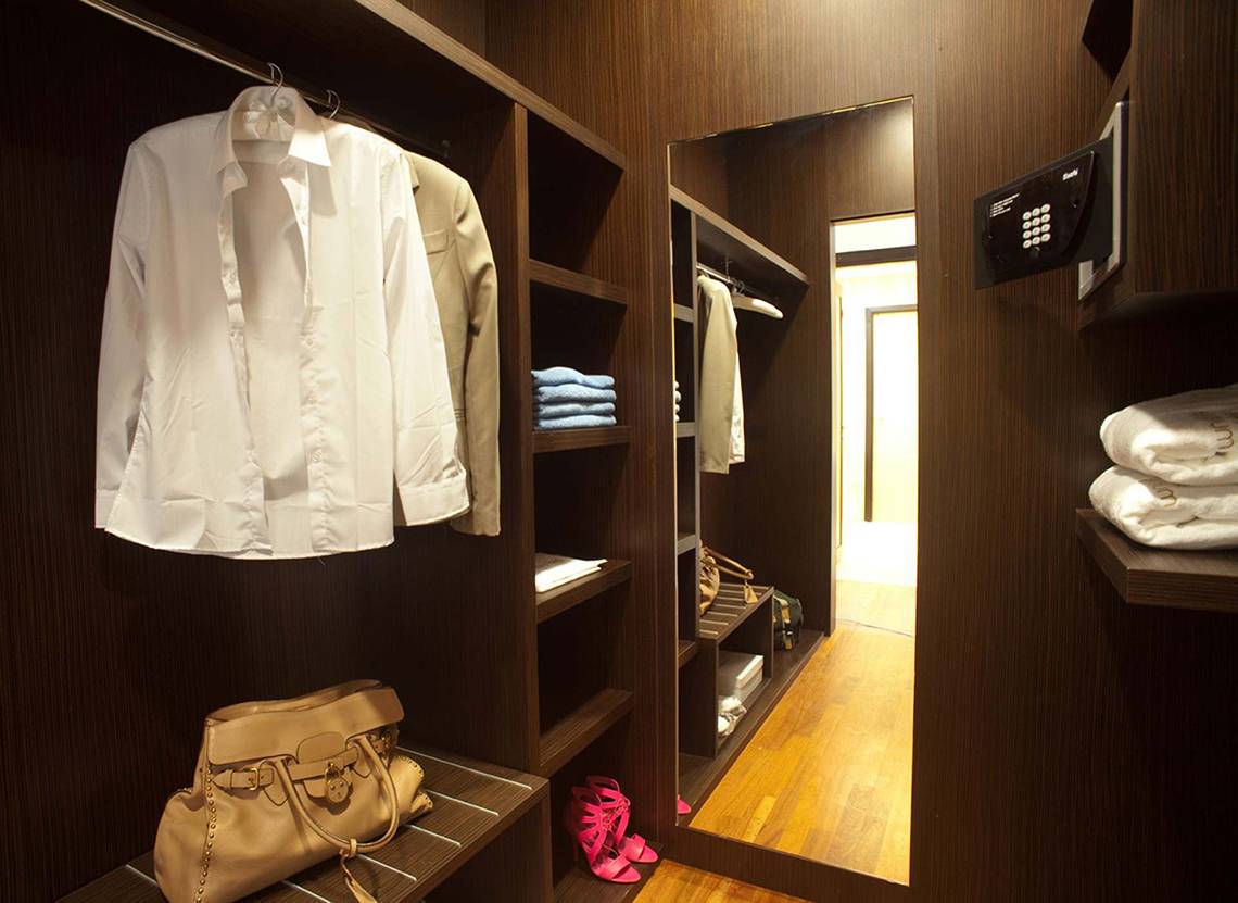 Innenansicht des Garderobenbereichs im Elysium Resort & Spa mit gut gefüllten Kleiderschränken, Schuhen und Handtasche.