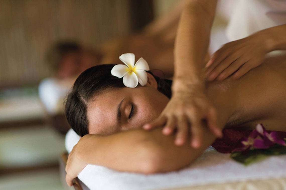Frau erhält Massage im Elysium Resort & Spa mit einer Blume im Haar.