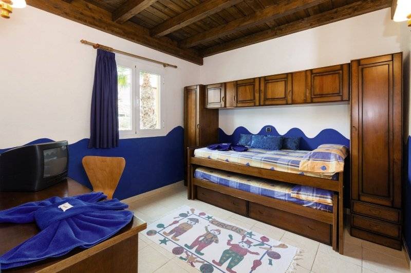 Innenansicht eines Schlafzimmers im Club Caleta Dorada Hotel mit Etagenbett, Fernseher und Tisch.