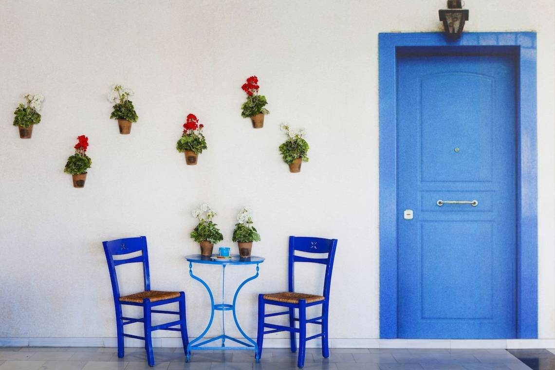 Eingang zum Kipriotis Village Resort mit blauen Stühlen und Blumen an der Wand