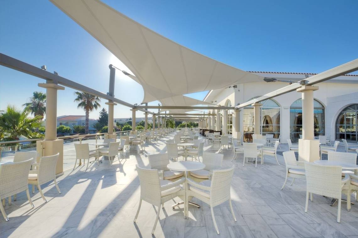 Außenbereich des Kipriotis Village Resort mit vielen weißen Tischen und Stühlen.