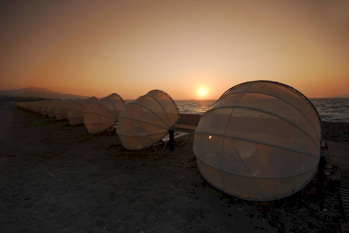 Reihe von transparenten Zelten am Strand des Kipriotis Village Resorts bei Sonnenuntergang.