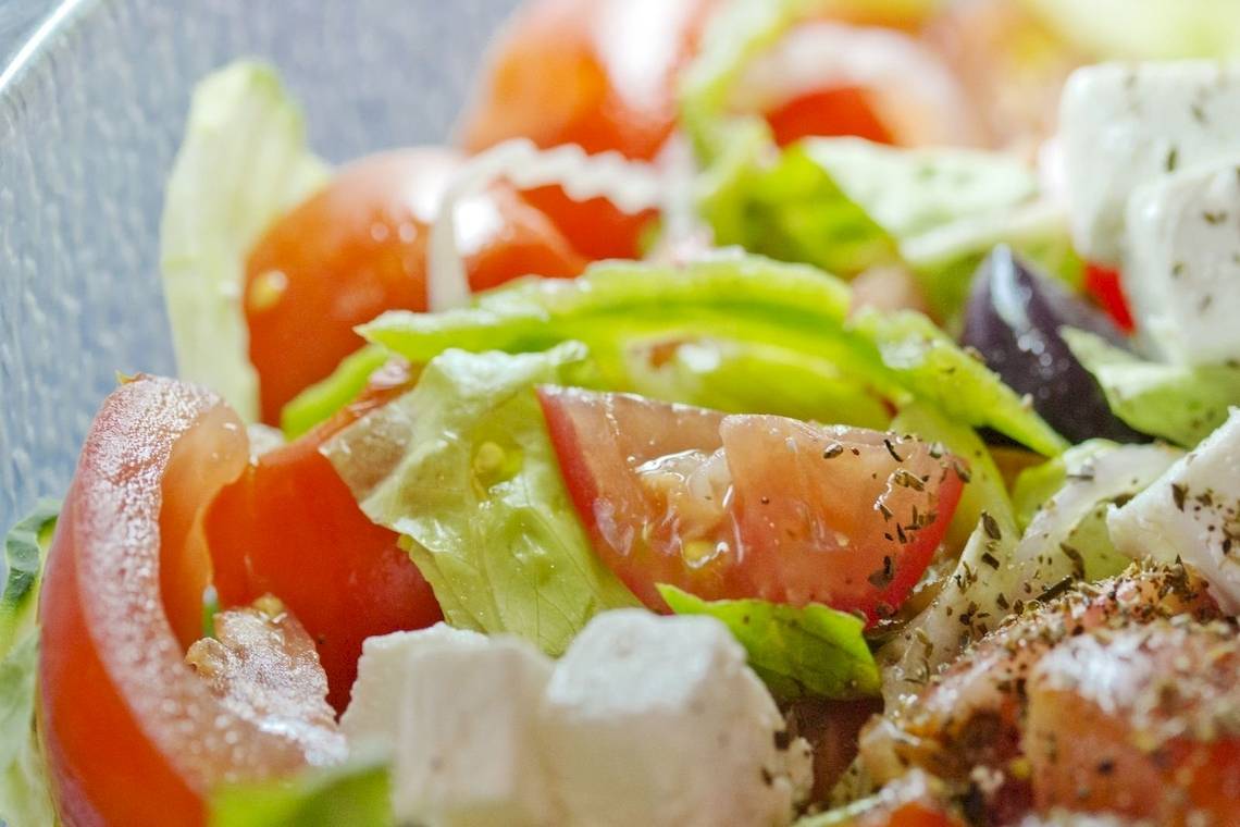 Nahaufnahme eines griechischen Salats mit Tomaten, Feta-Käse und Oliven in einem Glas