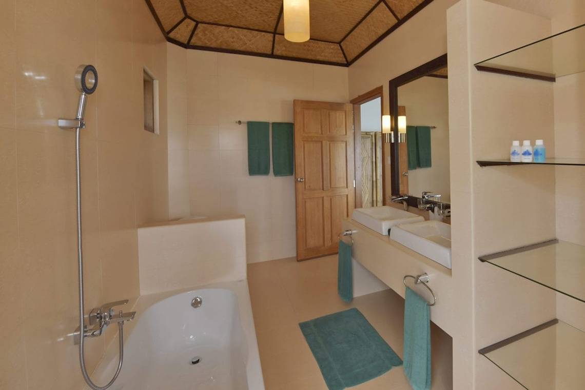 Badezimmer im Safari Island Resort mit Badewanne, Dusche, Waschbecken und grünen Handtüchern.