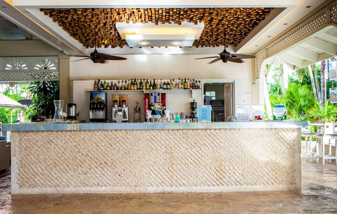 Innenansicht der Bar im Vista Sol Punta Cana Beach Resort & Spa mit gefliester Theke und Tropenpflanzen im Hintergrund.