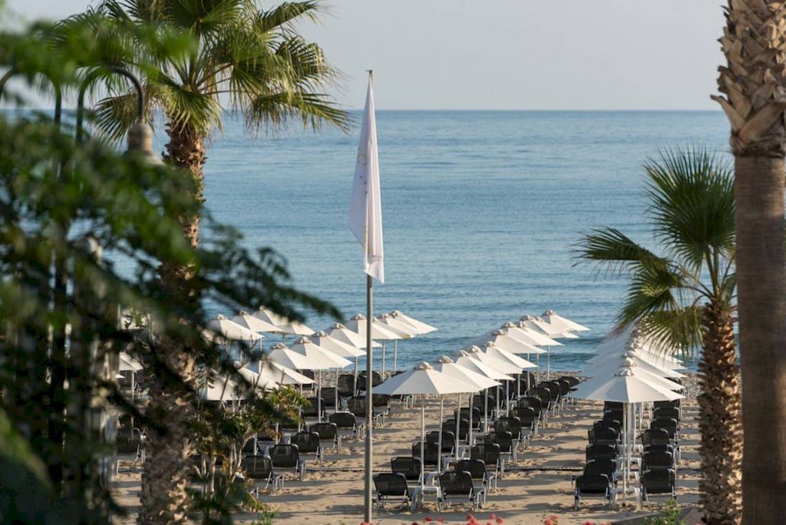 Aquila Porto Rethymno Hotel Strand mit weißen Sonnenschirmen und Liegestühlen