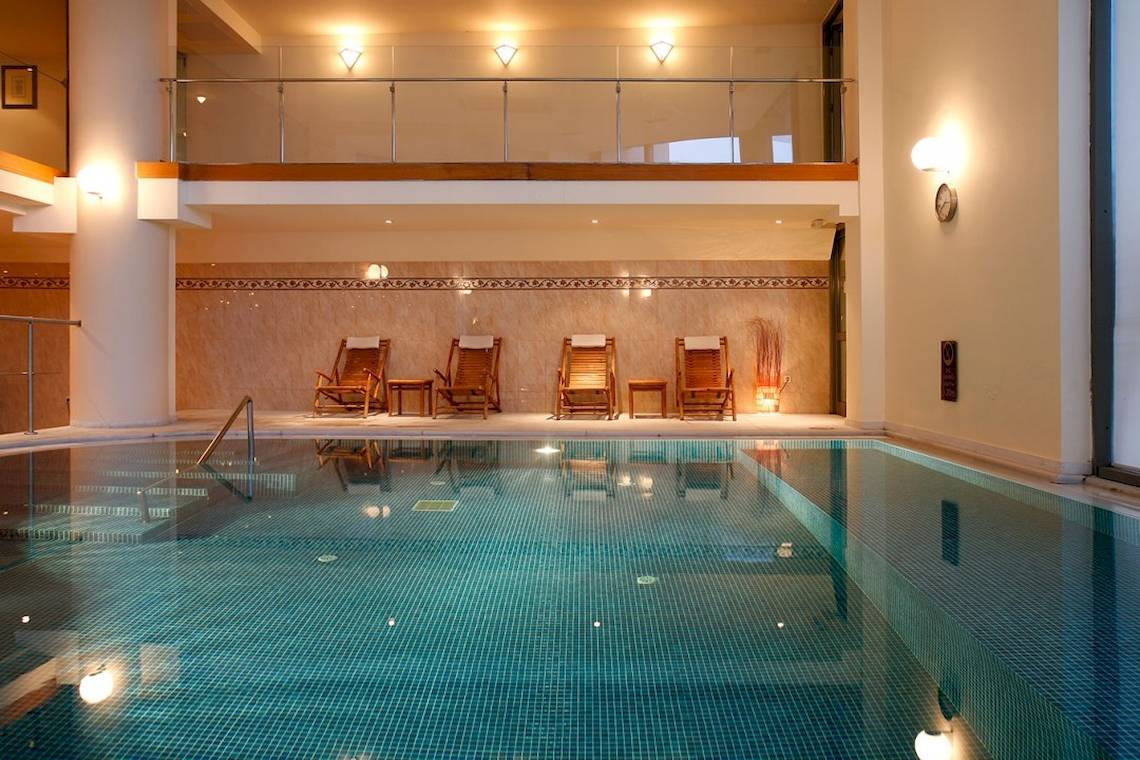 Innenpool des Aquila Porto Rethymno Hotels mit Liegen und Balkon