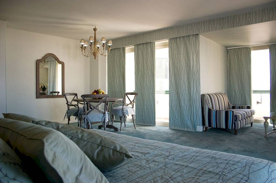 Schlafzimmer im Aquila Porto Rethymno Hotel mit Bett, Esstisch, Stühlen und Spiegel.