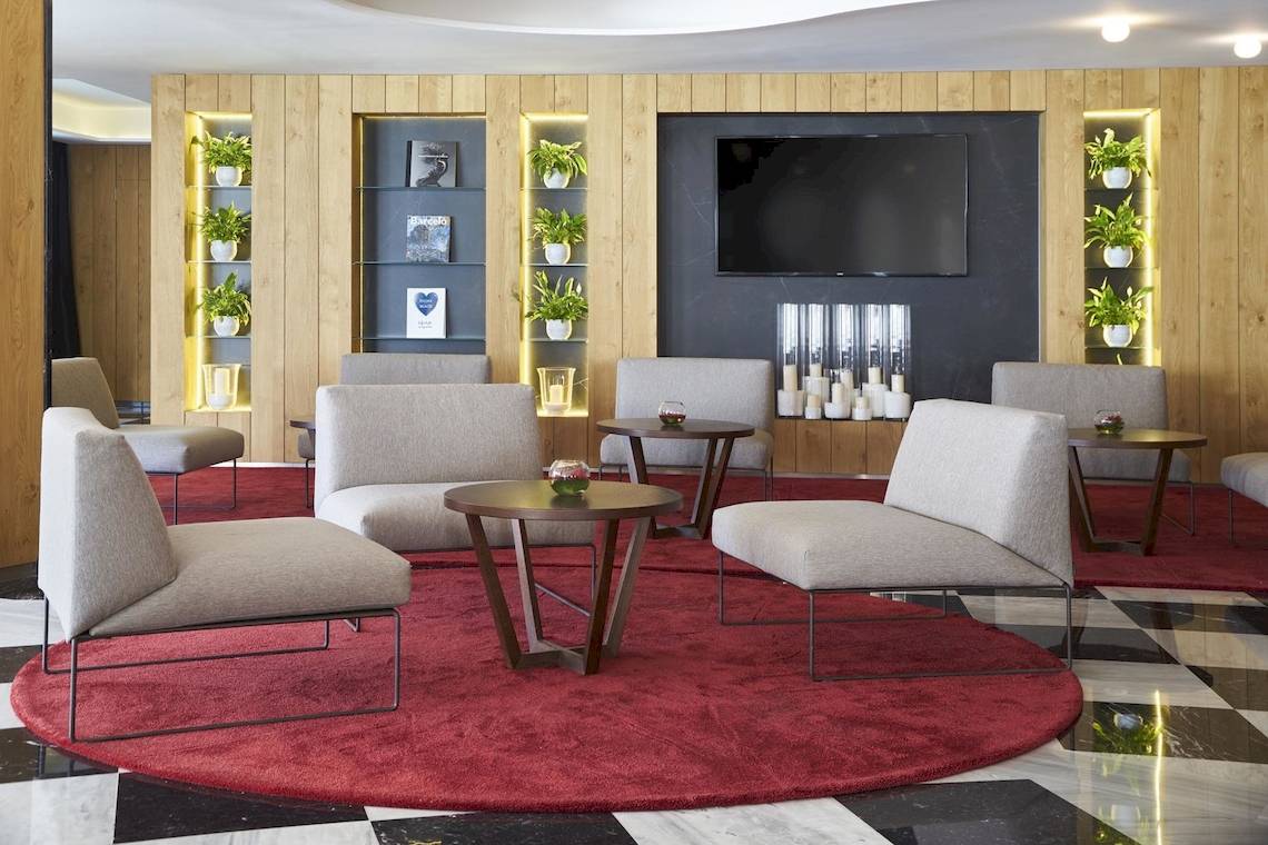 Lobby-Lounge im Pure Salt Garonda Hotel mit Sitzgelegenheiten und einem roten Teppich.