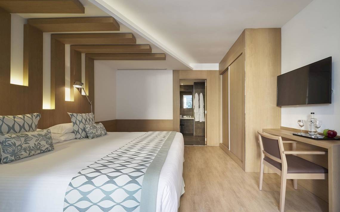 Innenansicht eines Hotelzimmers im Pure Salt Garonda mit Bett, Schreibtisch und Fernseher.