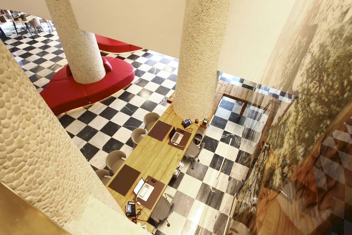 Aussicht auf die Lobby des Pure Salt Garonda Hotels mit schwarzen und weißen Bodenfliesen und roten Sitzmöbeln.