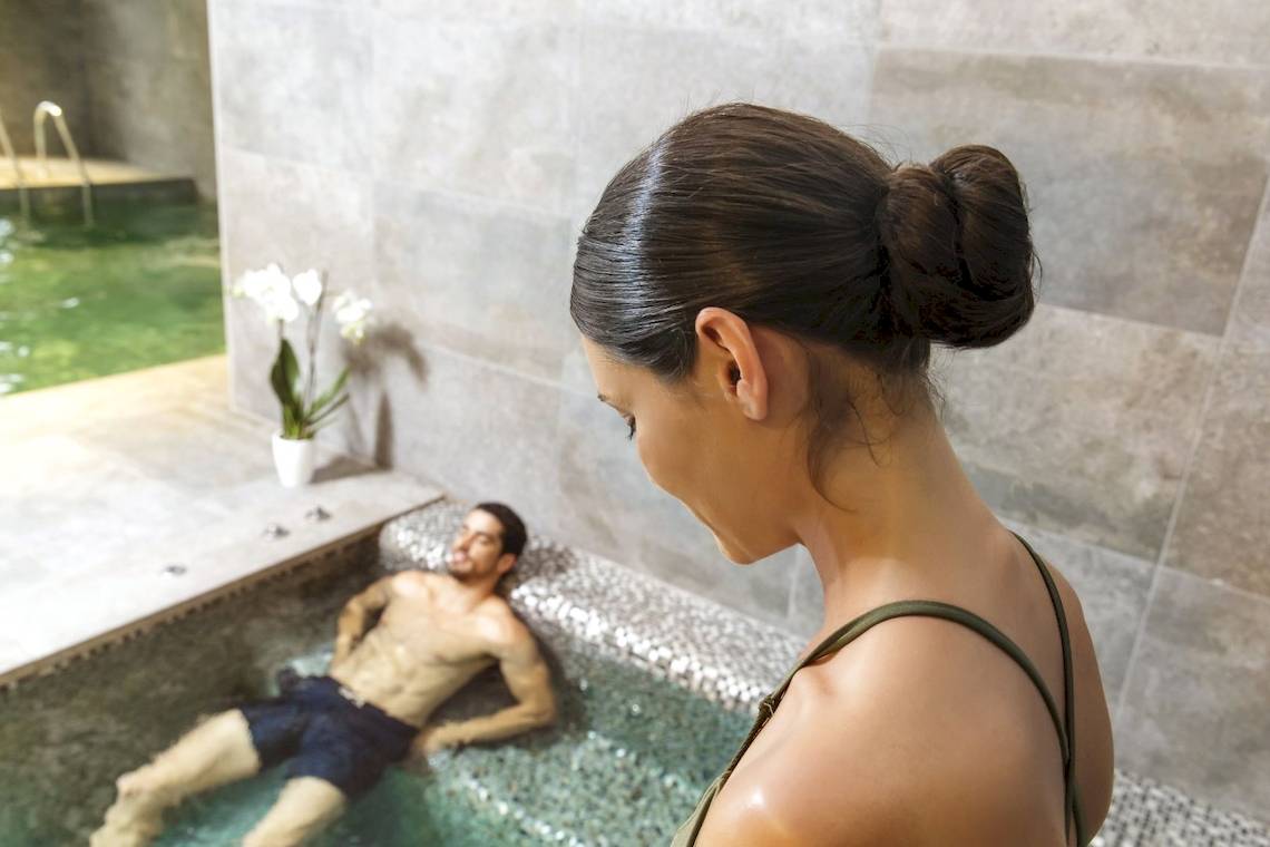 Eine Frau schaut in einen Innenpool, in dem ein Mann liegt, im Pure Salt Garonda Hotel.