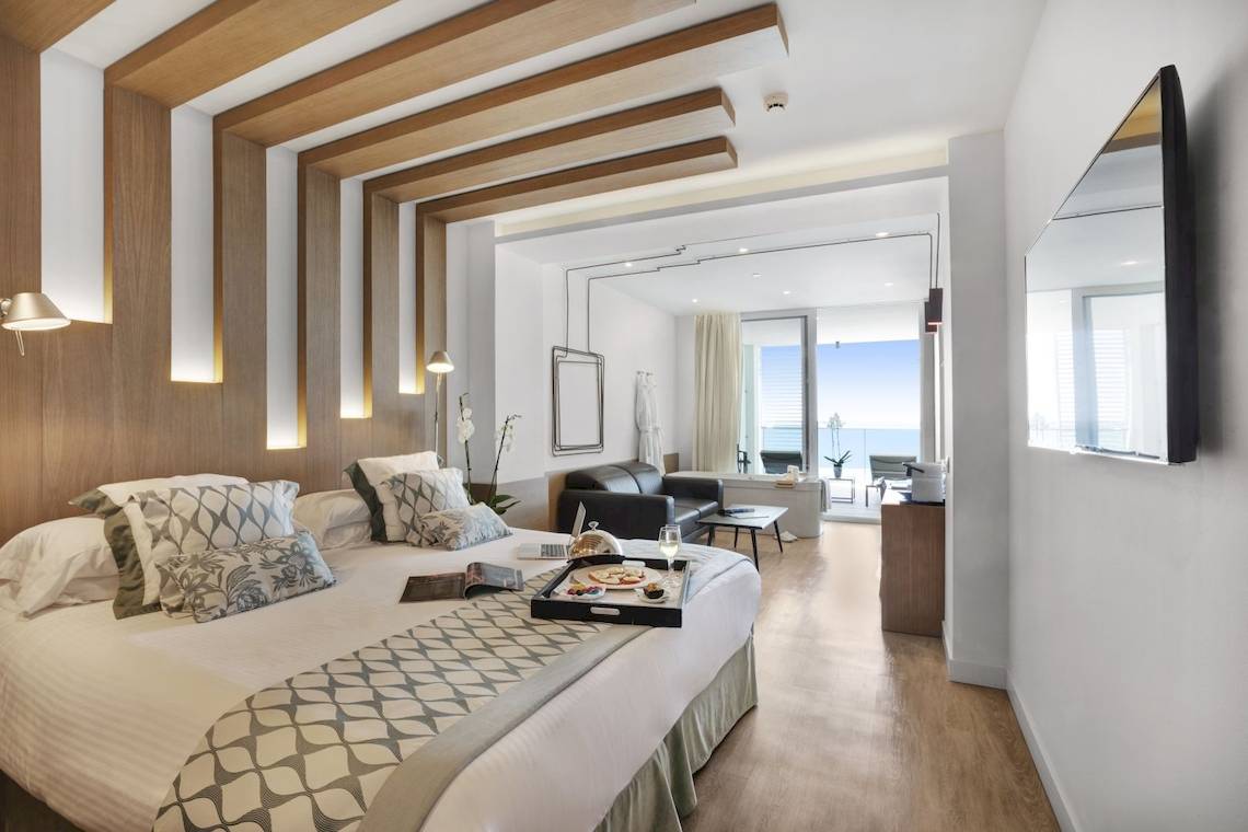 Innenansicht eines Zimmers im Pure Salt Garonda Hotel mit Bett, Möbeln und Balkon.