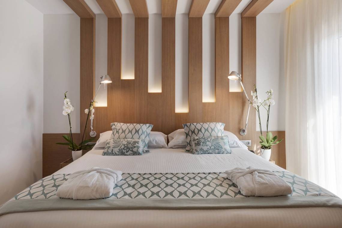 Schlafzimmer im Pure Salt Garonda Hotel mit Bett, Kissen, Nachttischen und Pflanzen.