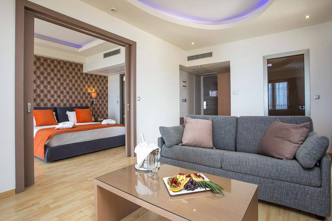 Wohnbereich im Pegasos Deluxe Beach Hotel mit einem Bett und einem Tisch.