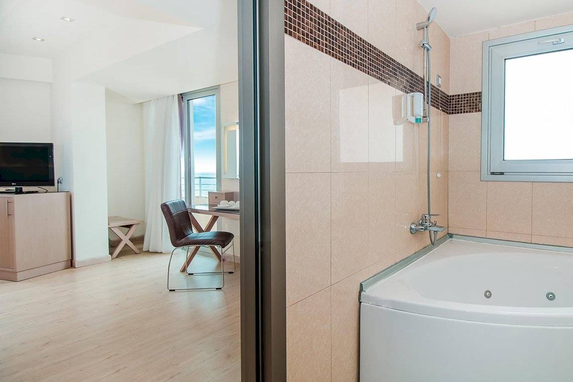 Badezimmer der Suite im Pegasos Deluxe Beach Hotel mit Badewanne, Dusche und Blick auf das Meer.