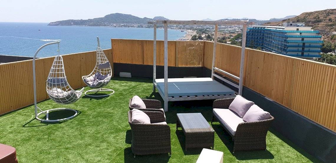 Dachterrasse des Pegasos Deluxe Beach Hotels mit Blick auf das Meer und moderne Gebäude.