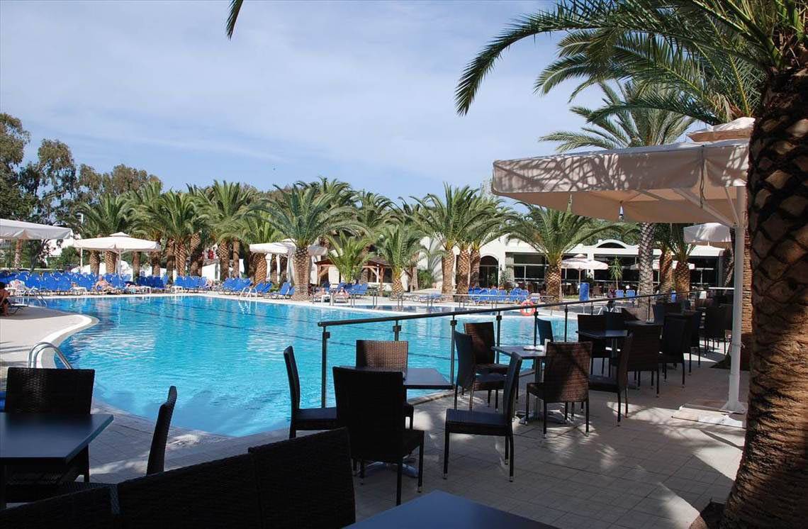 Außenpool-Terrasse des Kipriotis Hippocrates Hotels mit Sonnenschirmen, Tischen und Stühlen.