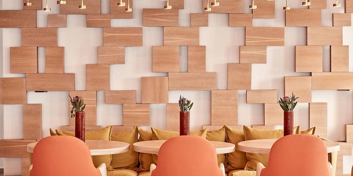 Lobby des Myconian Naia Hotels mit Sofas und Tischen vor einer Holzwand