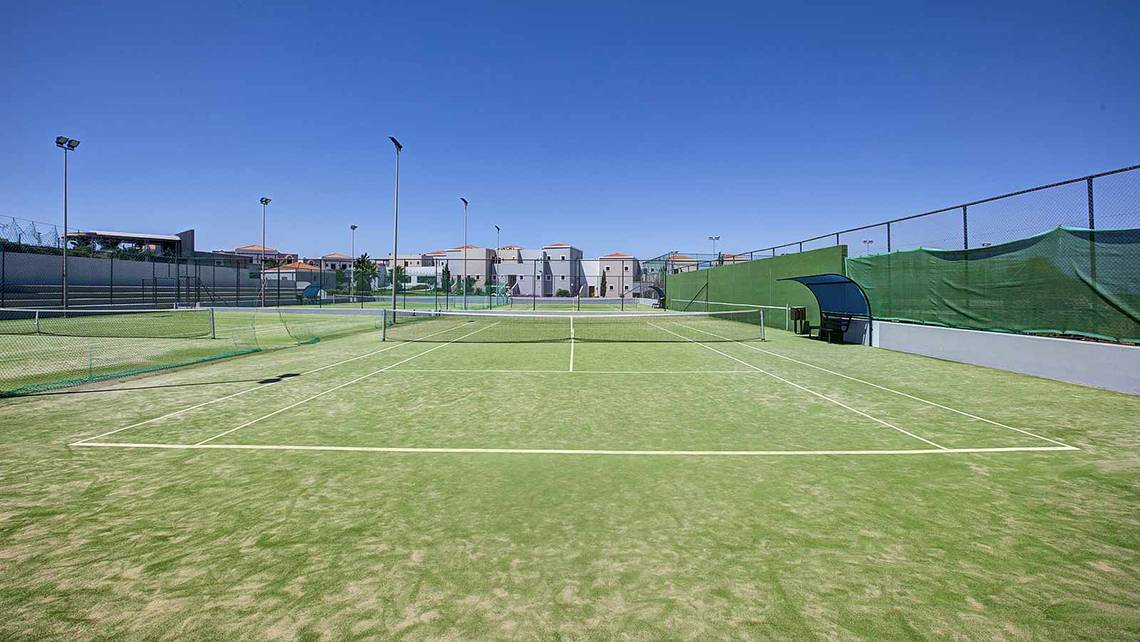 Tennisplatz im Atlantica Marmari Palace mit leeren Spielfeldern und umliegenden Gebäuden.