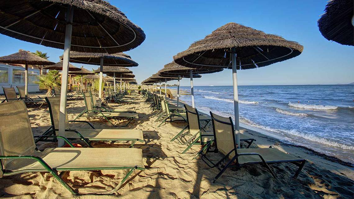 Strand des Atlantica Marmari Palace mit vielen Liegen und Sonnenschirmen
