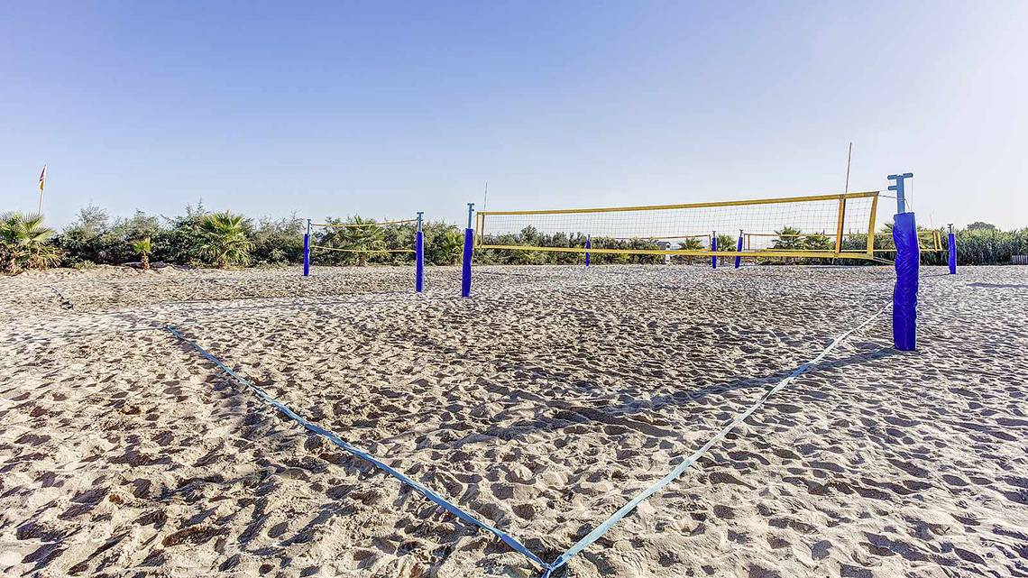 Volleyballfelder auf einem Sandstrand mit blauen Netzen und Pfosten.
