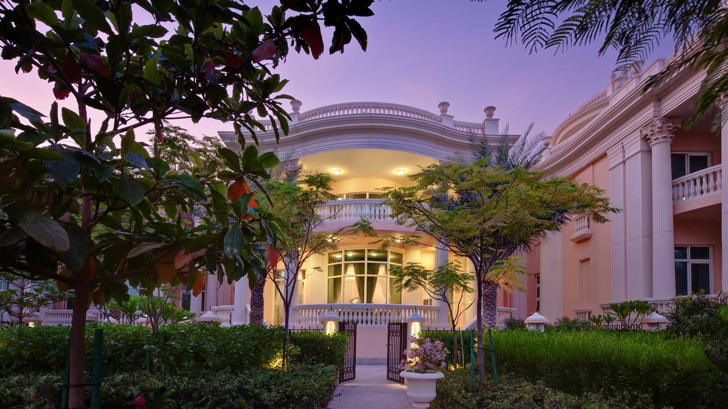 Außenansicht des Kempinski Hotel Residences Palm Jumeirah mit gut beleuchtetem Eingang und Garten.
