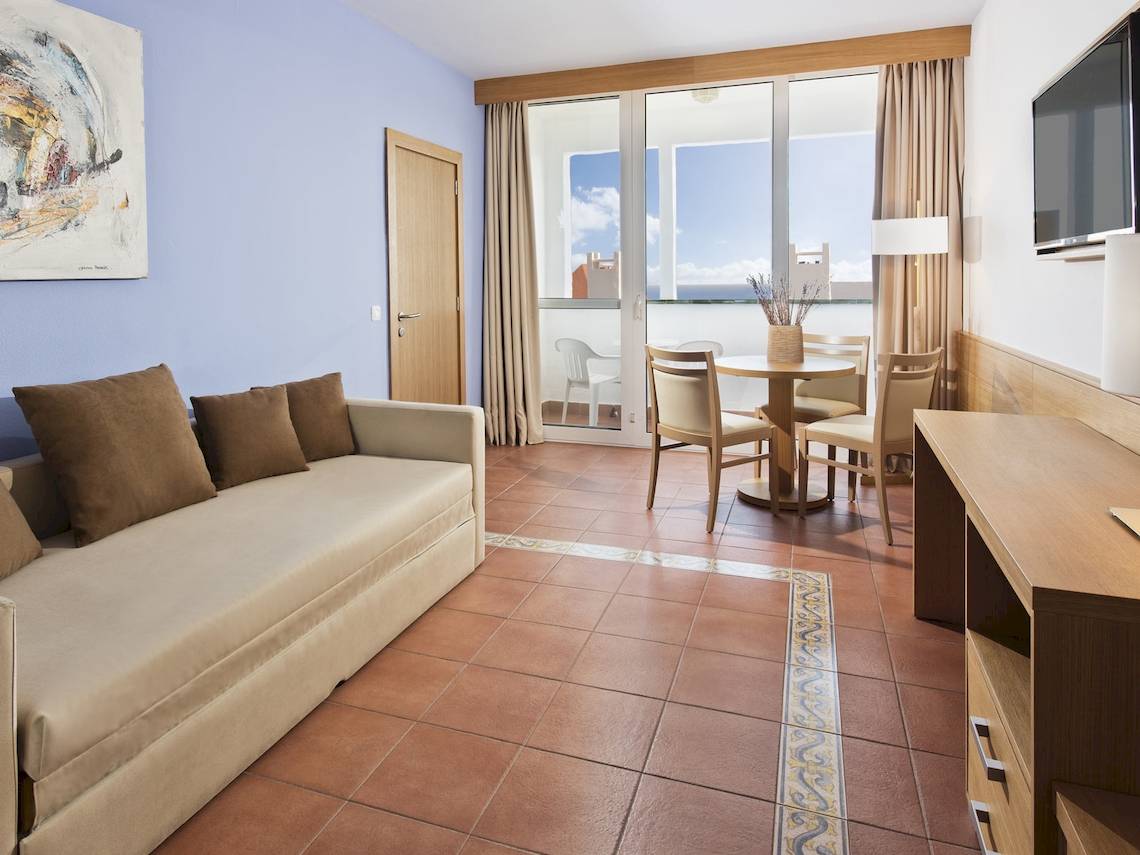 Wohnbereich im Fuerteventura Princess Hotel mit Sofa, Esstisch und Meerblick.