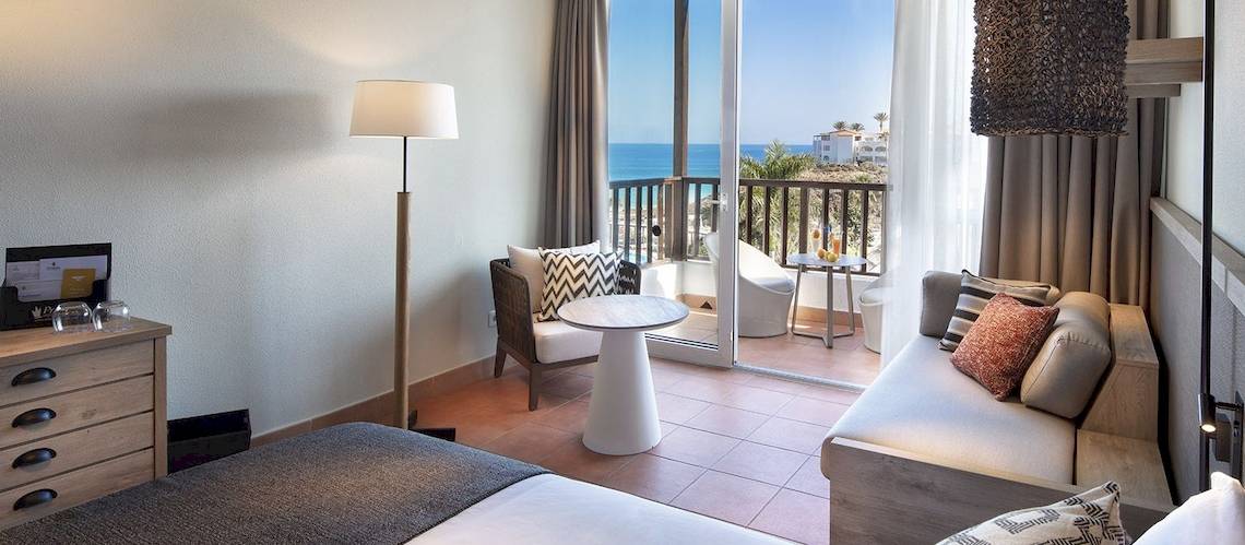 Innenansicht einer Suite im Fuerteventura Princess Hotel mit Blick auf den Ozean und einem möblierten Balkon.