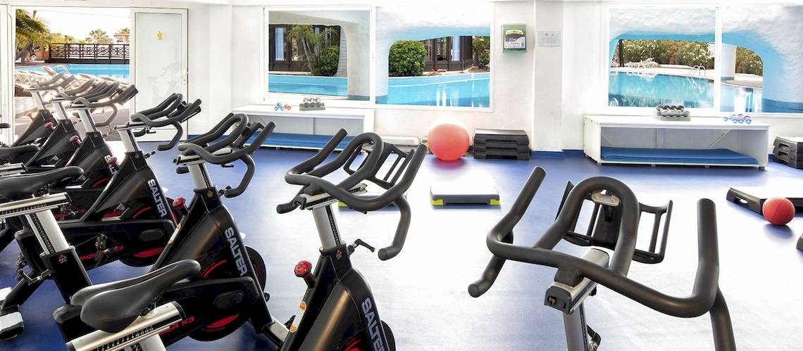 Fitnessraum im Fuerteventura Princess Hotel mit Blick auf den Pool und Trainingsgeräten.