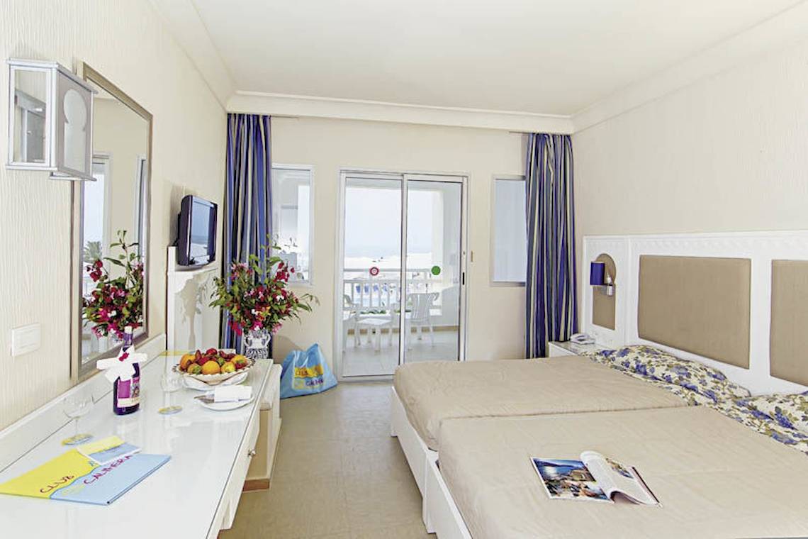 Ein modernes Hotelzimmer mit zwei Betten, einem Balkon und Meerblick.