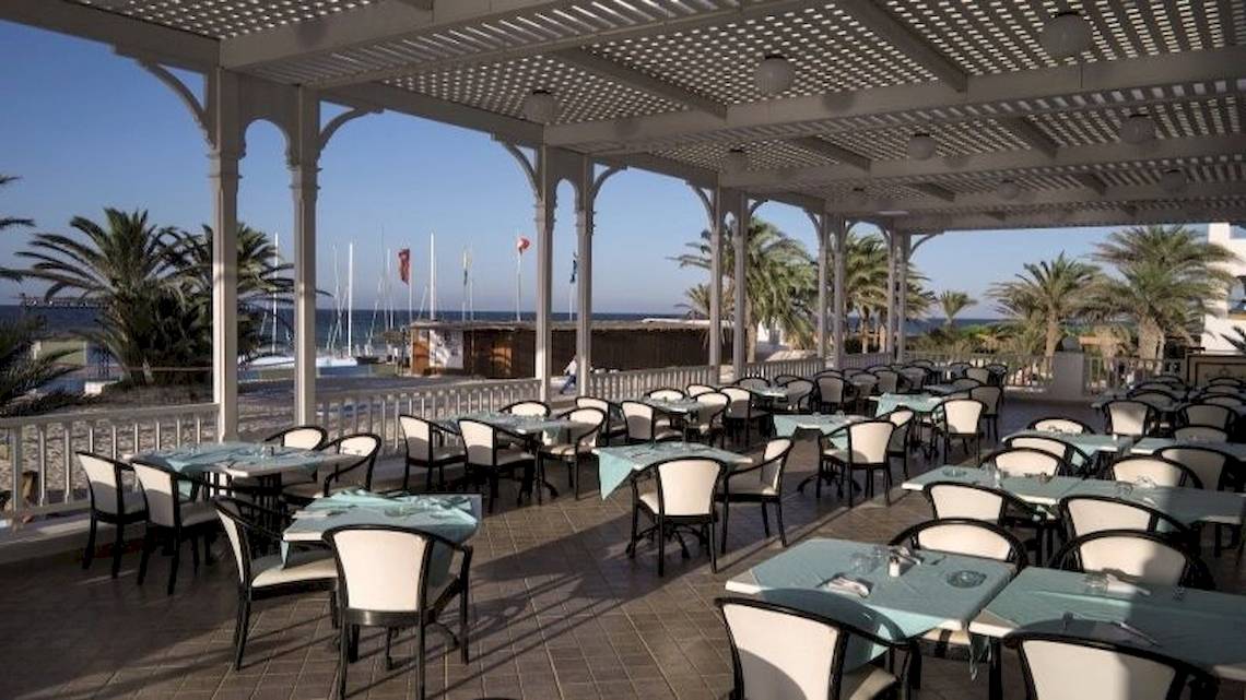 Terrasse des Calimera Yati Beach Hotels mit Blick auf das Meer und Palmen