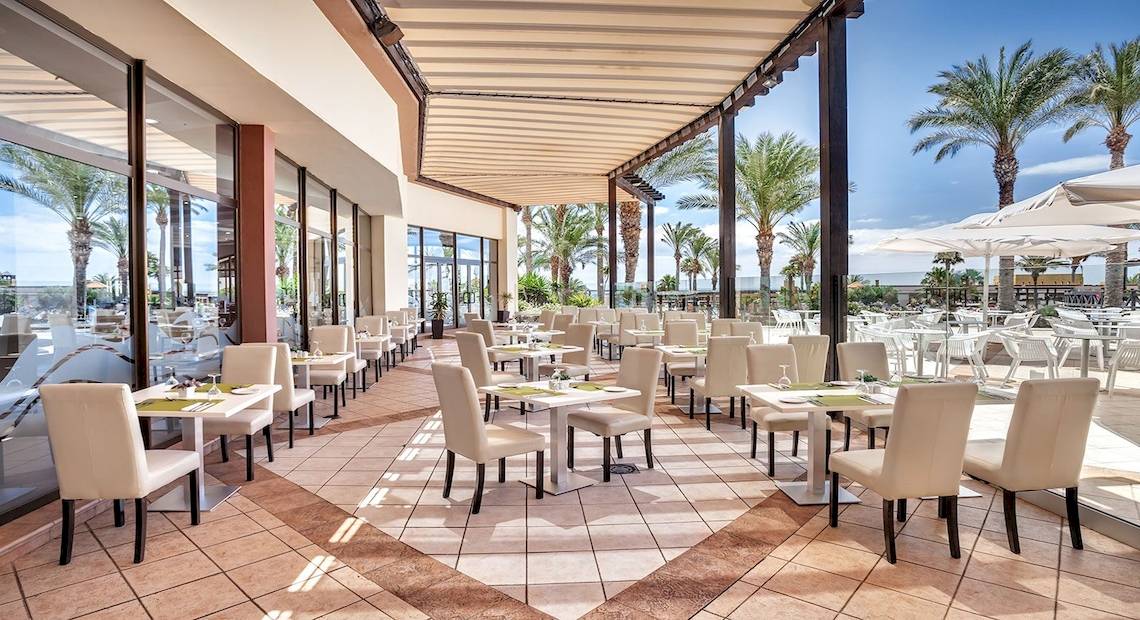 Innenansicht des Restaurants im Occidental Jandia Mar Hotel mit vielen Tischen und Stühlen unter einem Markisendach.