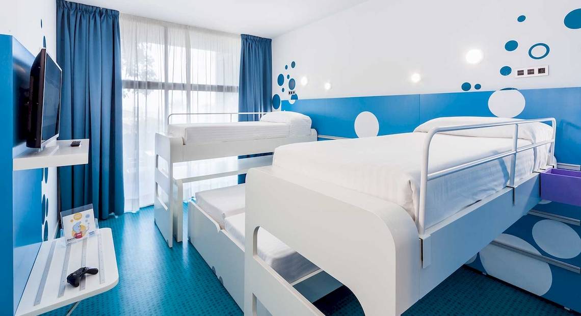 Doppelzimmer im Occidental Jandia Mar Hotel mit zwei Etagenbetten, blauen Wänden und weißen Punkten.