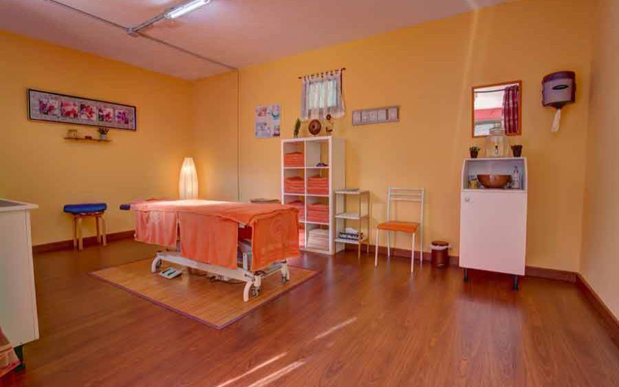 Behandlungsraum im SBH Monica Beach Resort mit orangefarbener Liege, Möbeln und Dekoration.