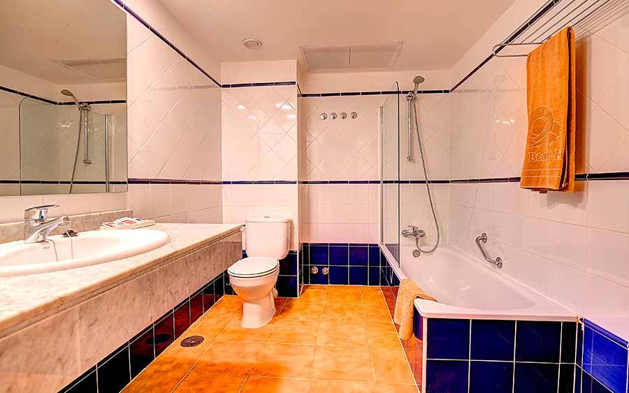 Badezimmer im SBH Monica Beach Resort mit Badewanne, Toilette und Waschbecken.