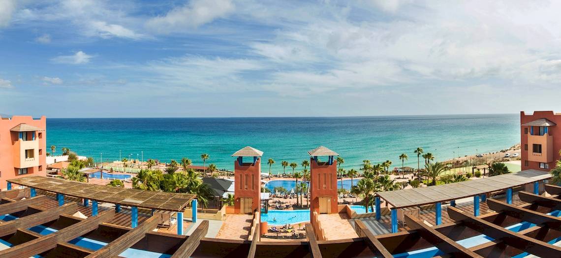 Aussicht auf das Meer vom H10 Tindaya Hotel aus, mit Gebäuden und Swimmingpools.