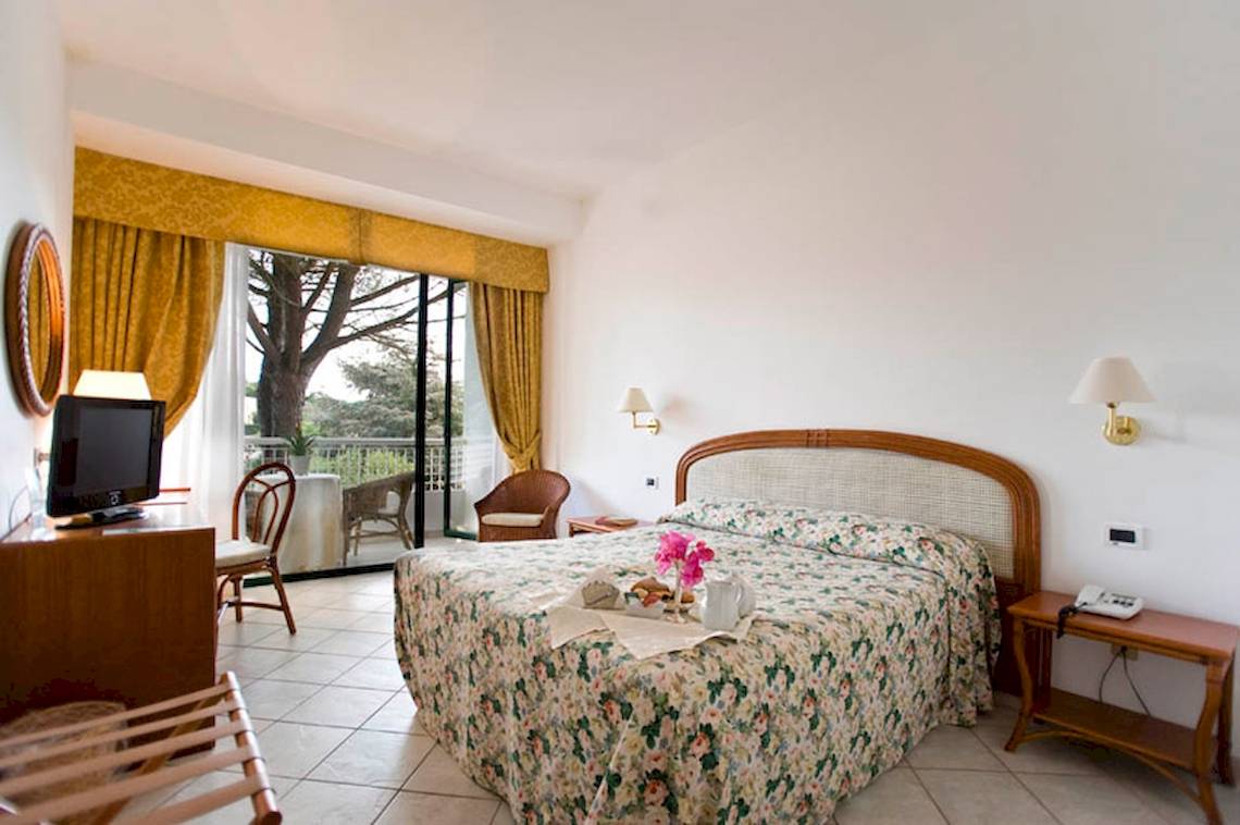 Ein Schlafzimmer im Sierra Silvana Hotel mit Balkon, Fernseher, und Blumenbettwäsche.