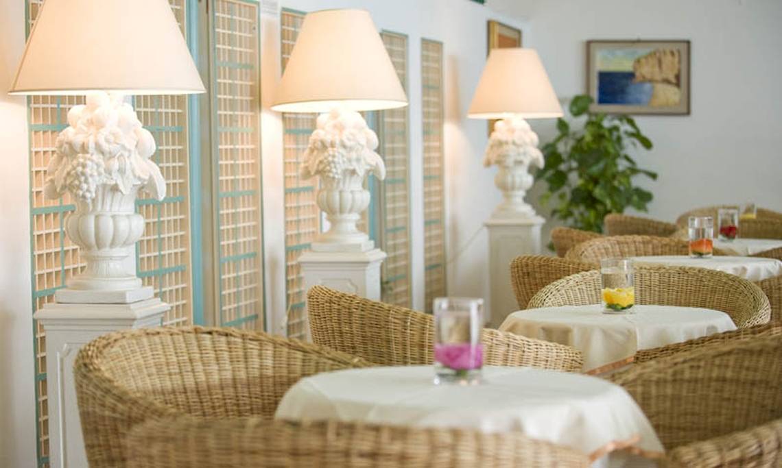 Innenbereich des Sierra Silvana Hotels mit gepolsterten Stühlen und Tischen, weißen Lampen und Kunstwerken.