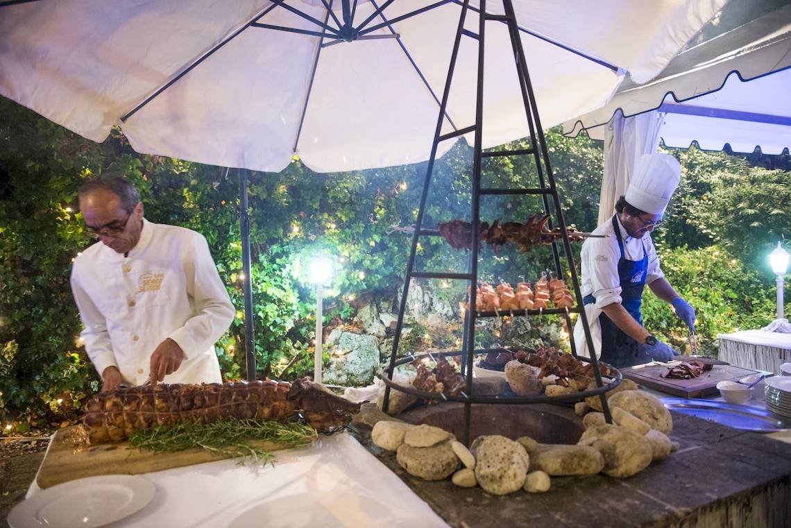 Zwei Köche bereiten Speisen auf einem Grillbereich im Freien im Hotel Sierra Silvana zu.