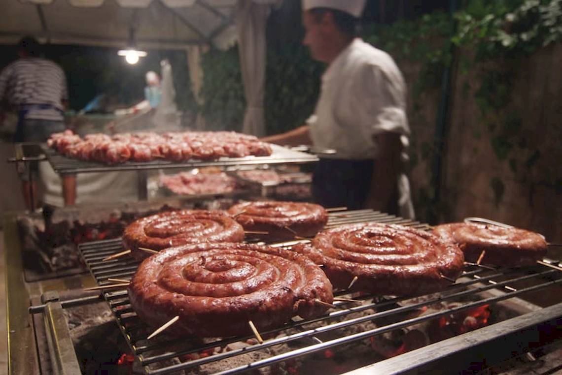 Grillen im Hotel Sierra Silvana mit einem Koch, der Würstchen auf einem Grill zubereitet.