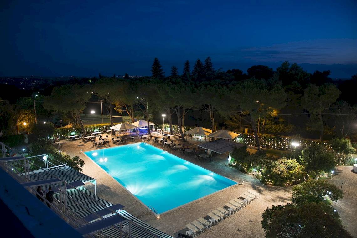 Luftaufnahme des beleuchteten Außenpools und der Terrasse des Hotels Sierra Silvana bei Nacht