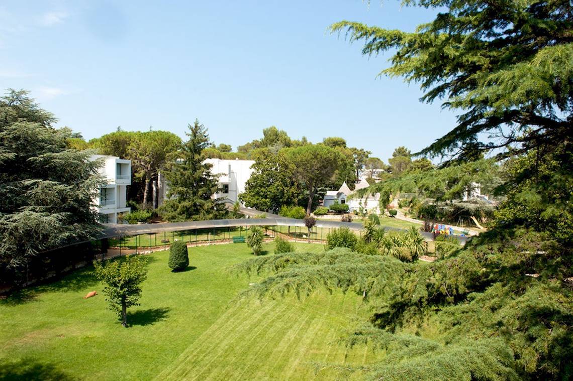 Außenbereich des Sierra Silvana Hotels mit Rasen, Bäumen und Gebäuden.