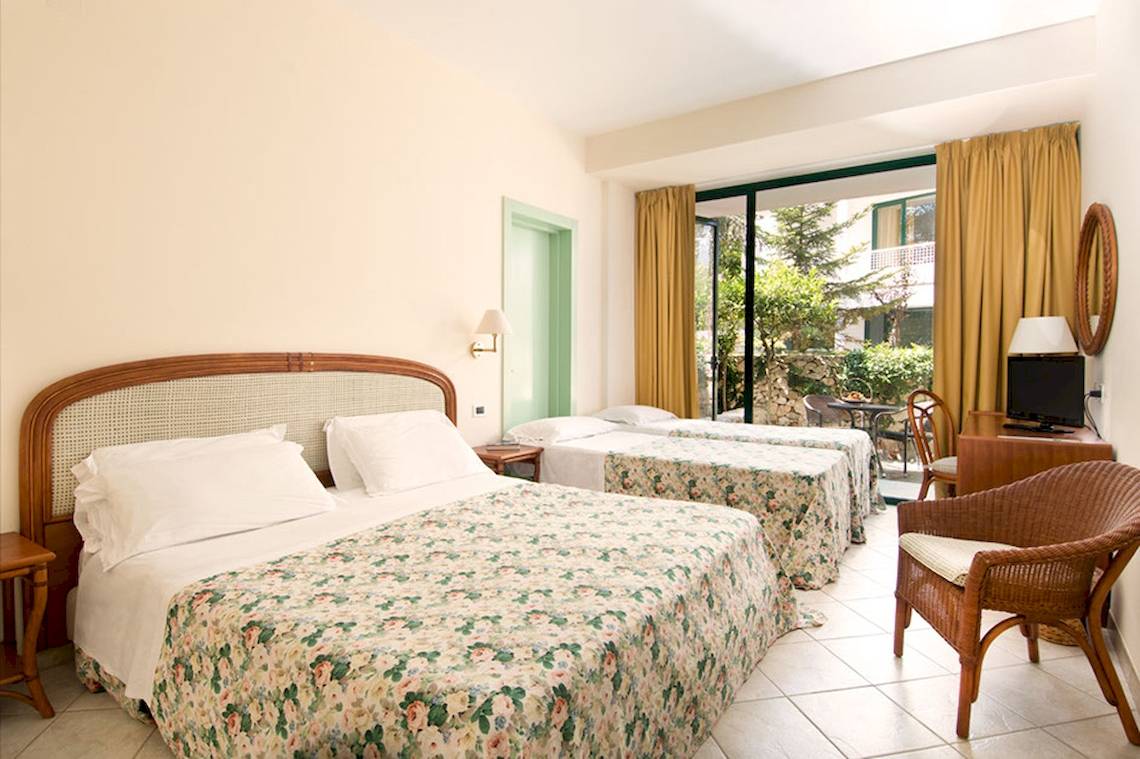 Zimmer im Sierra Silvana Hotel mit zwei Betten und einem Fenster, das auf einen Gartenblick hinausgeht.