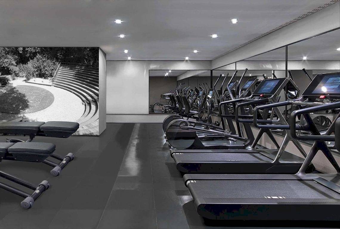 Fitnessraum im Alkyna Lifestyle Beach Resort mit modernen Laufbändern und einer großen Wandprojektion.