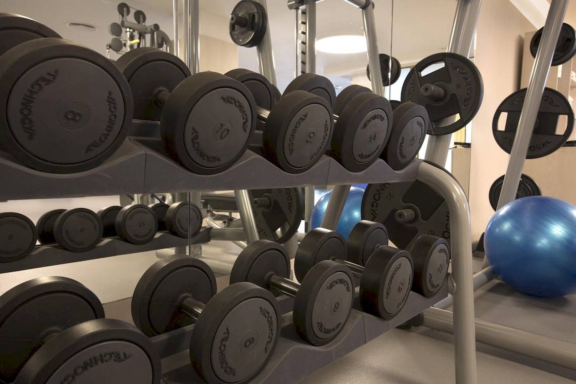 Fitnessstudio mit verschiedenen Gewichten und einem blauen Meditationsball