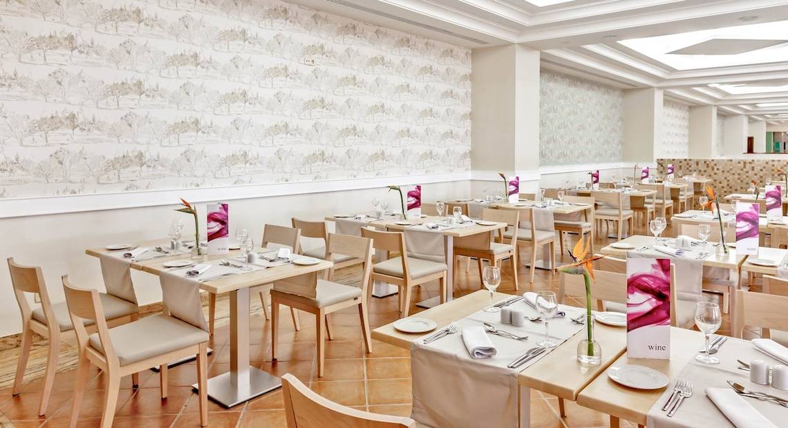 Innenansicht des Restaurants im Occidental Jandia Playa Hotel mit gedeckten Tischen und weißen Wänden.